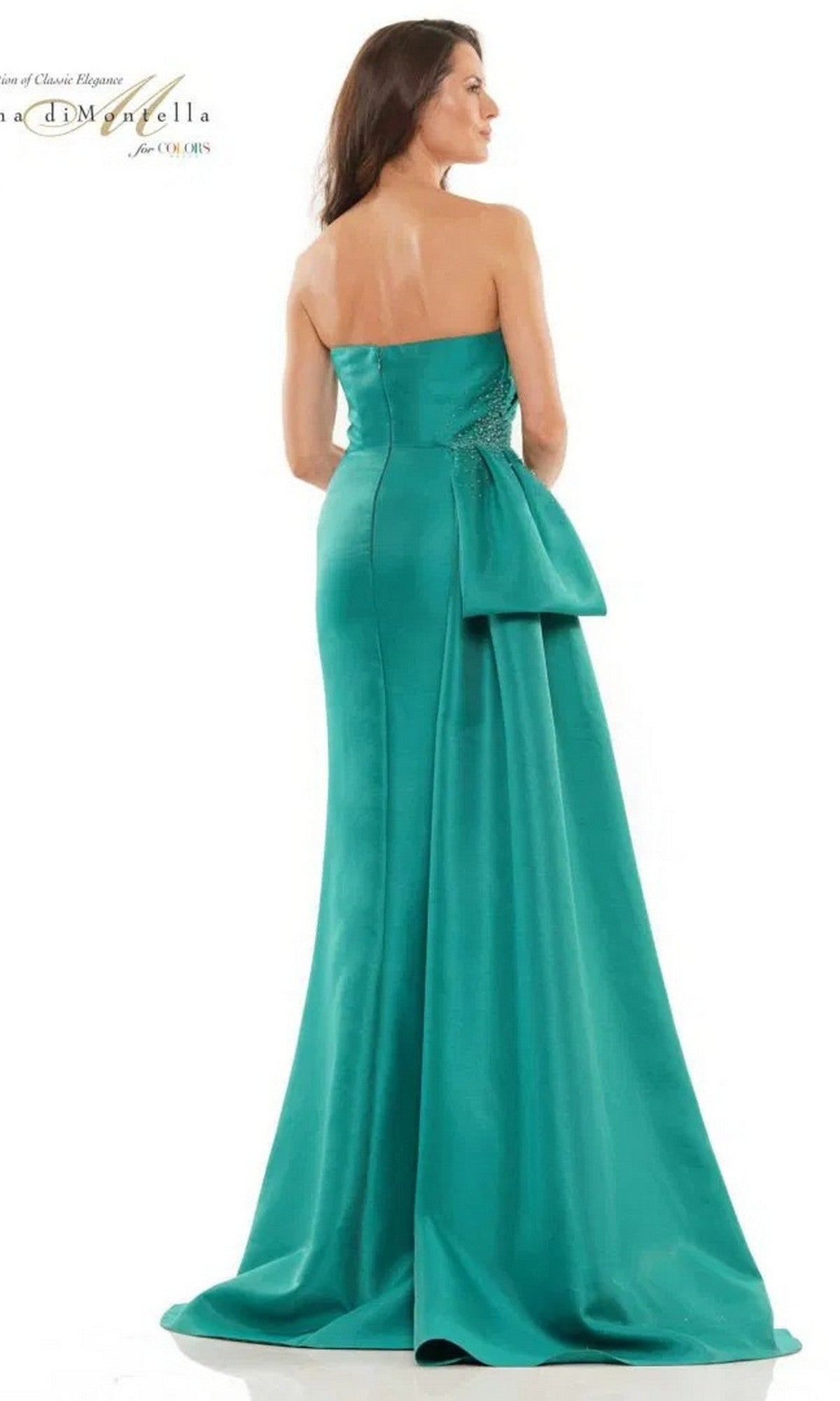 A woman faces away, wearing the Rina Di Montella RD2750—a strapless, floor-length teal sheath gown featuring a large back bow and elegant train.